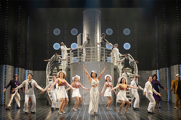 The cast of Anything Goes poses on the ship’s deck in front of the grand staircase, dressed in 1930s nautical costumes. Ensemble includes sailors, passengers, and lead performers mid-chorus pose. Shaw Festival 2025. Photo by David Cooper.