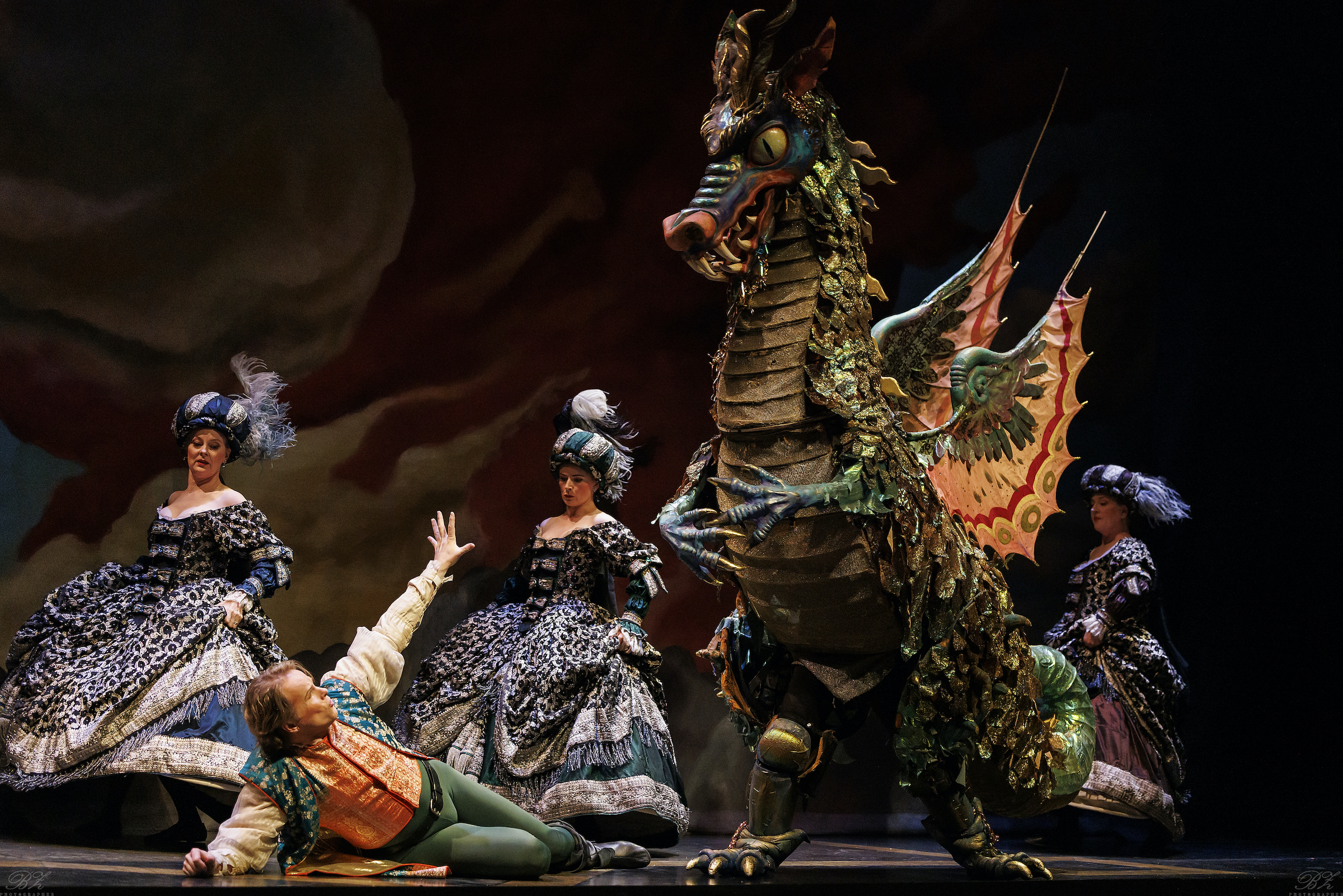 Colin Ainsworth as Tamino on the ground, attended by the Three Ladies, with the dragon from Opera Atelier’s The Magic Flute (2025).
