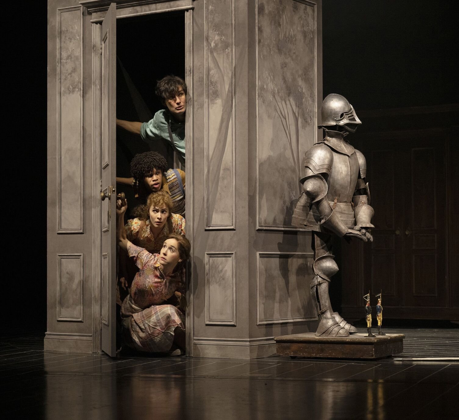 The four Pevensie children peek out from the wardrobe, wide-eyed with wonder, as they discover the magical land of Narnia. Shaw Festival 2025. Photo by David Cooper.
