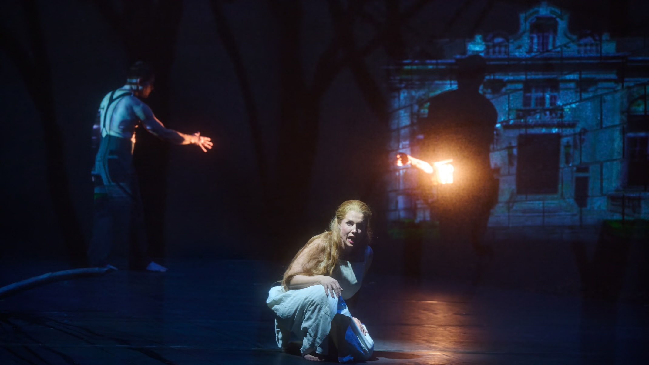 The Woman crouched on the floor, a vision of a man and the house behind her.