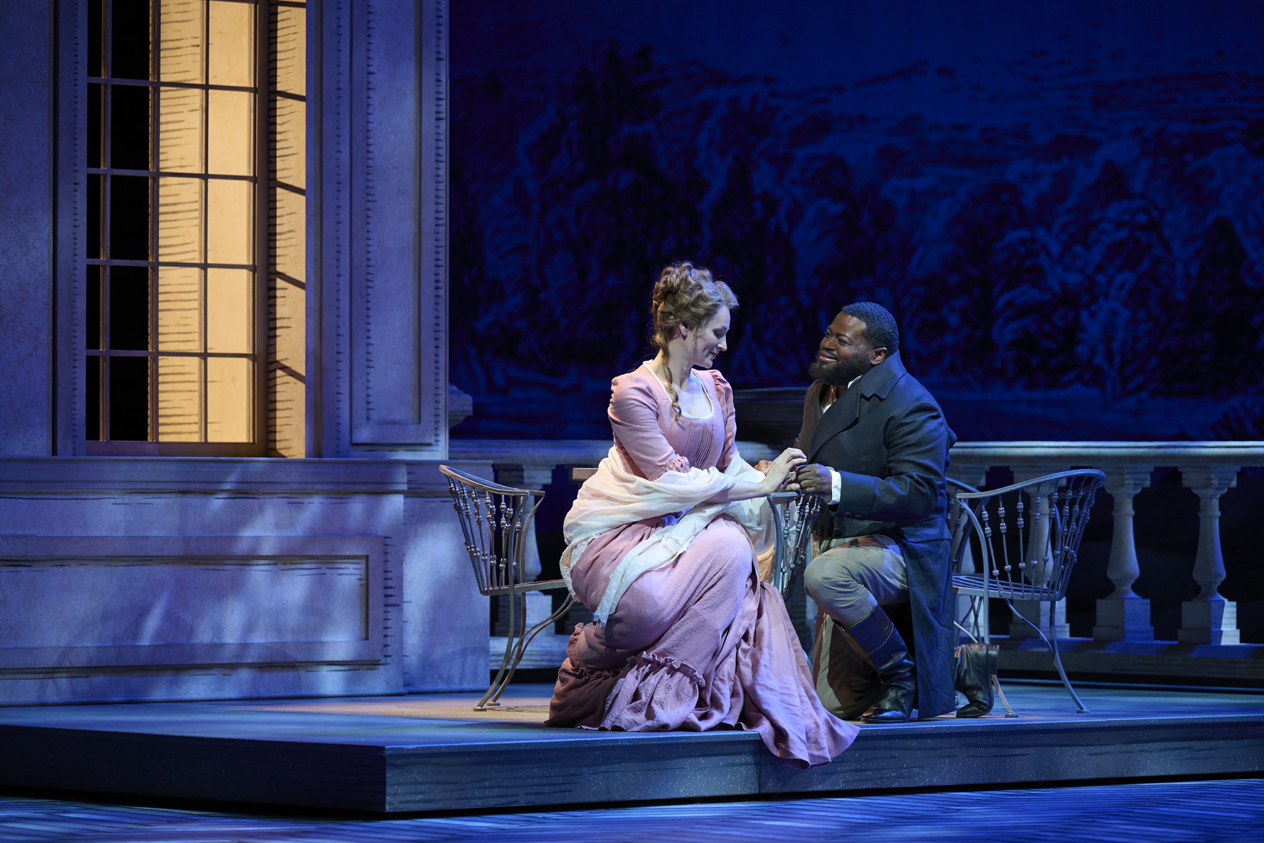 Charlotte and Werther sitting intimately close on the terrace in the moonlight.